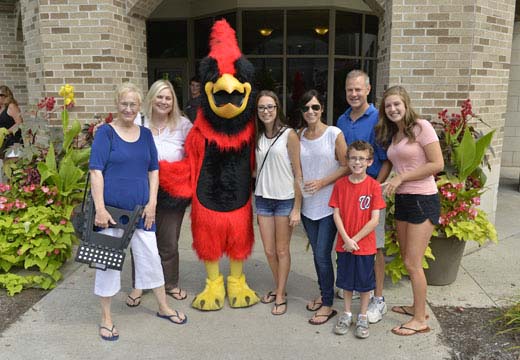 Family poses for camera with Cardinal in front of Campus Center.